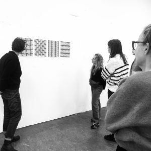 Groepje deelnemers bekijkt abstract werk dat aan de muur hangt